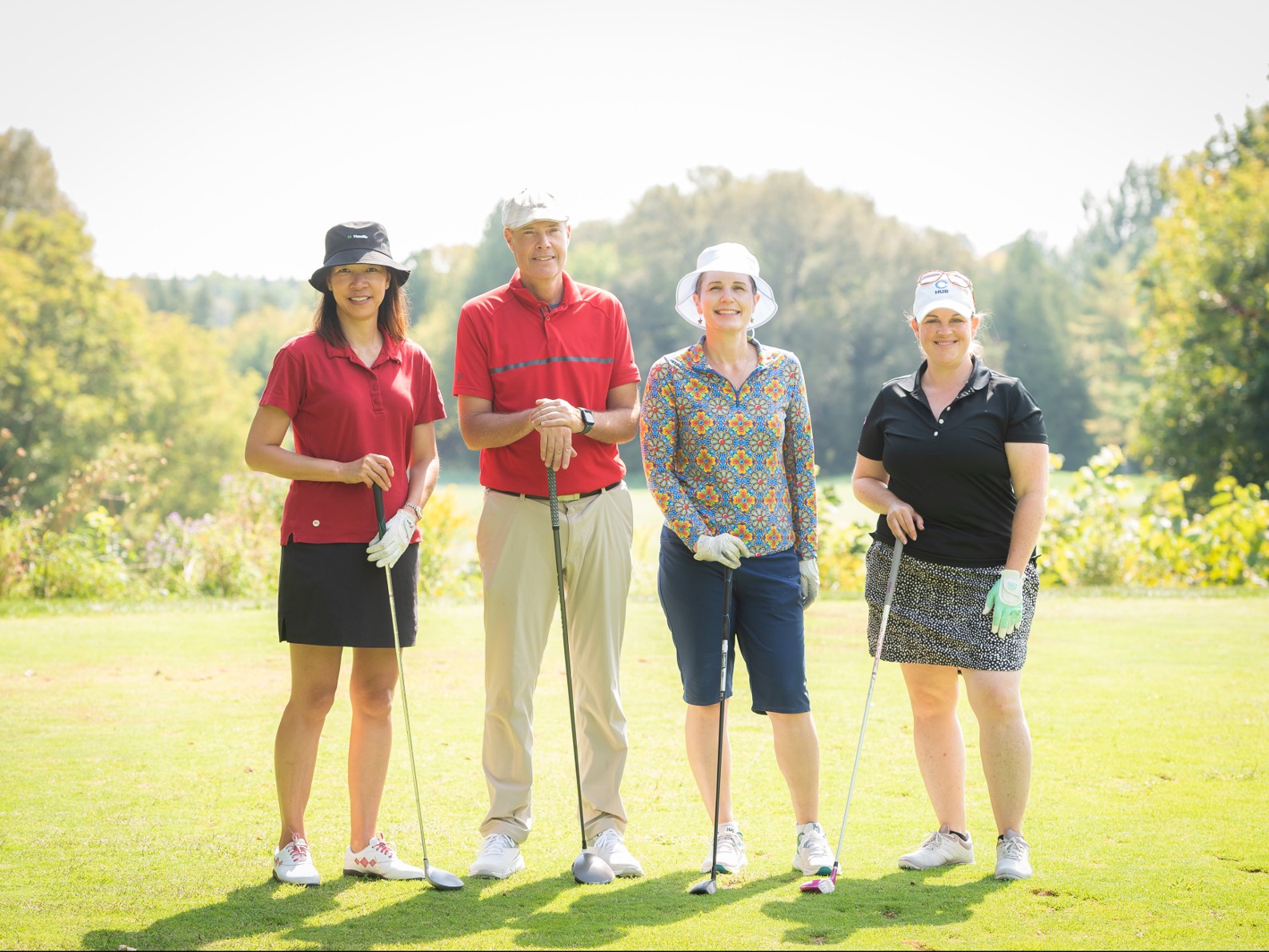 Elaine Wong, John Dickie, Dr. Marisa Finlay and Kim Stewart standing together on a golf course with a club